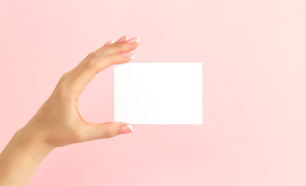 istock Woman hand holding blank white mock-up card on pink background 1299622030