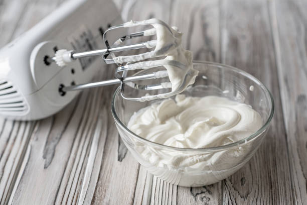 Woman whipping cream using electric hand mixer on the gray rustic wooden table Woman whipping cream using electric hand mixer on the gray rustic wooden table electric whisk stock pictures, royalty-free photos & images