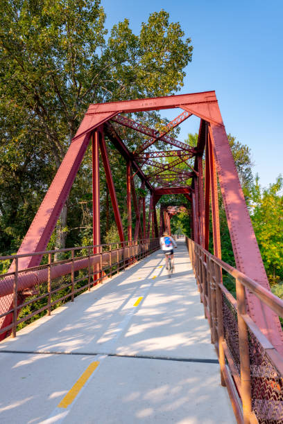 Bike path bridge with a cycler passing over Bicyclist travels over a bridge on Boise"u2019s green belt boise river stock pictures, royalty-free photos & images