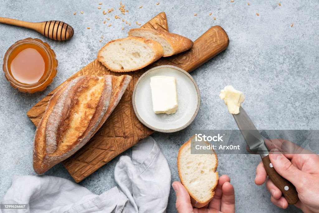White artisan bread and butter White artisan bread and butter. Male hand spreading butter on bread Butter Stock Photo
