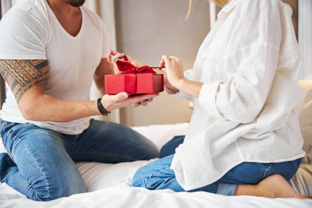 istock Blonde female unwrapping a present given by her spouse 1299626725