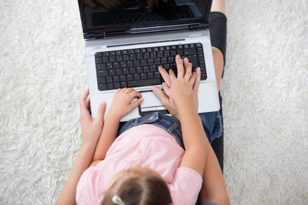 istock Little girl using a laptop with her mother at home 1299629143