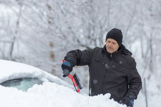 istock Man giving his best to remove snow and ice from a car 1299630611