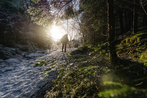Man hiking outdoors in forest during a snowy winter day