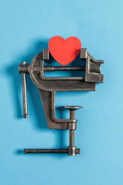 Red Heart In Vise Grip on blue background