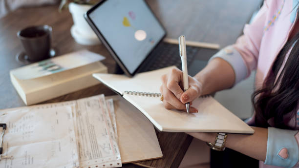 istock Close up. Business woman taking notes in notebook on desk at office. 1299632406