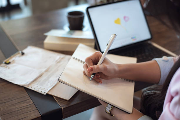 istock Close up. Woman taking notes on desk at cafe. 1299632434