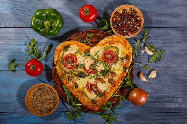 istock Heart shaped pizza for two, fresh vegetables and spices 1299633064