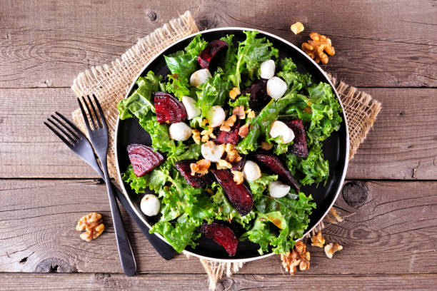 istock Healthy kale and beet salad with cheese and walnuts, table view on a rustic wood background 1299633676