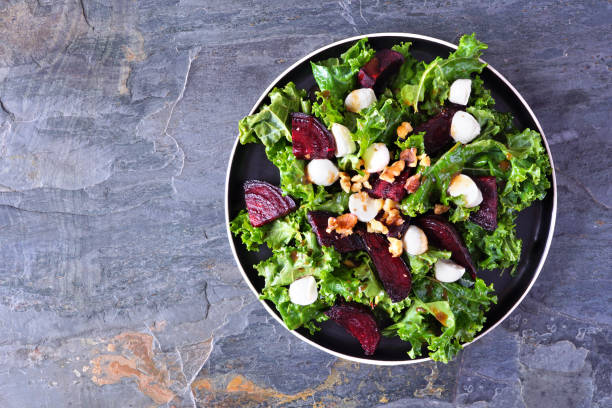 istock Healthy kale and beet salad with cheese and walnuts over a dark background 1299634406