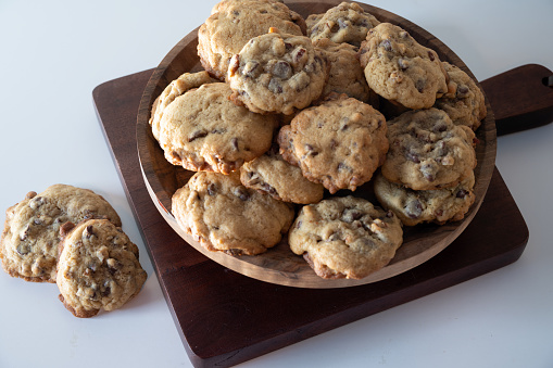 Chocolate chip cookies on a wooden tray ready to eat with a wooden cutting board