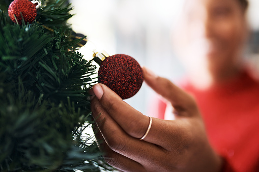 Closeup shot of an unrecognisable woman decorating a Christmas tree at home