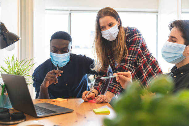 pessoas usando máscara facial no trabalho em pequenos home office - nova situação de trabalho, trabalho inteligente de negócios durante a pandemia coronavírus - computer team young adult smart casual - fotografias e filmes do acervo