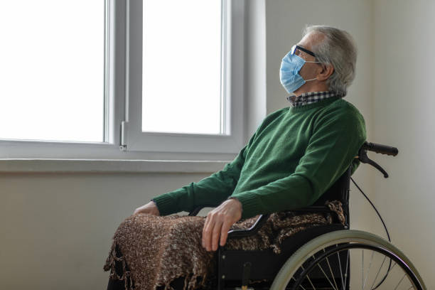 istock Senior man looking out the window while sitting in his wheelchair 1299637099