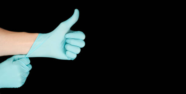 istock Hand in blue glove isolated on black with thumb up. 1299637411