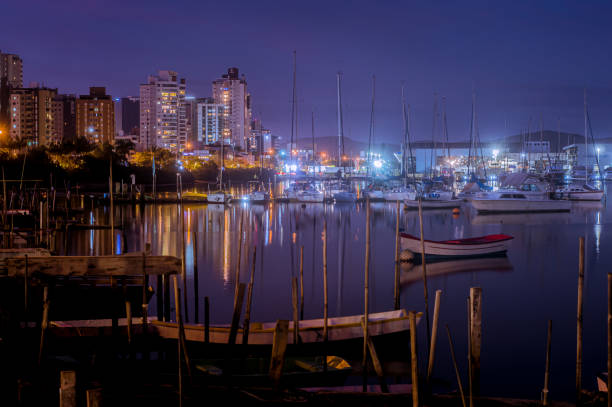 cidade de itajaí santa catarina brasil à noite com barcos na água e luzes refletidas na água - sailboat moored blue nautical vessel - fotografias e filmes do acervo