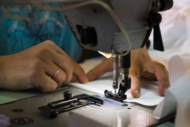 istock Woman hands with fabric at sewing machine 1299637737