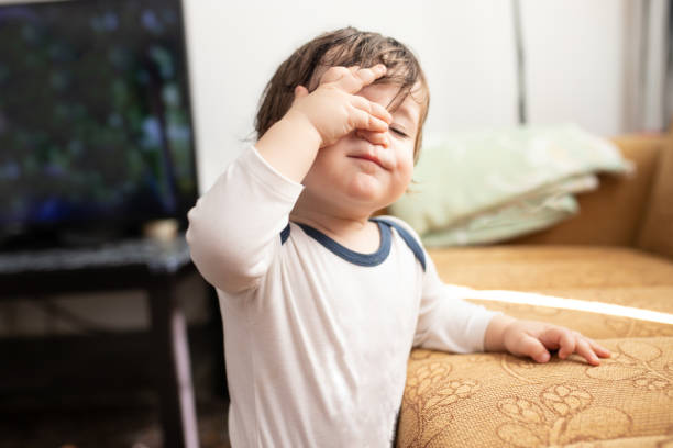 istock Baby holding his forehead, suffering from headache 1299638613