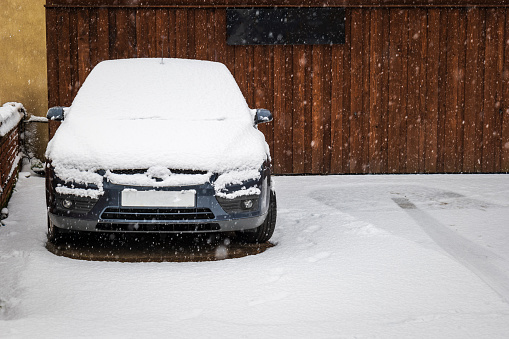 Car parked on british street under winter snow fall in england uk.