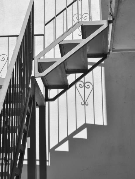 istock Metal stairs in black and white. Shadows on the wall. Creative minimal composition. 1299640963