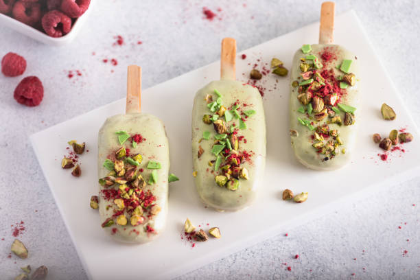 istock Ice cream sticks with white chocolate, fruit, pistachios and colored sugar on a white background. 1299642871