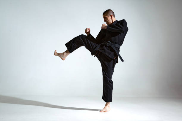istock Fighting guy in black kimono fighter shows jiu jitsu technique on studio background with blank space, mix fight concept 1299644929
