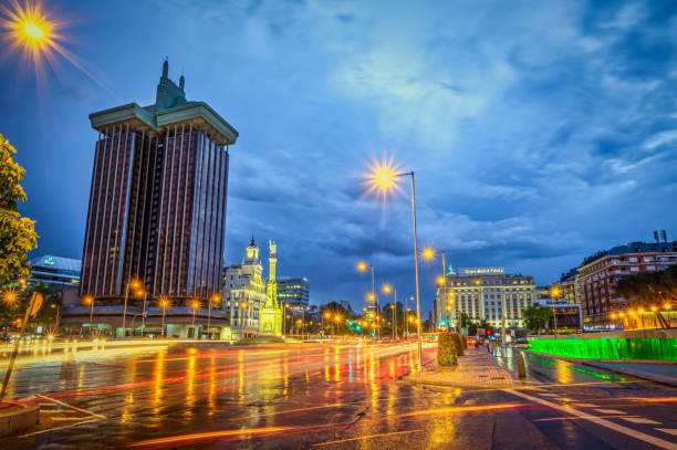 Madrid, Spain - May 7, 2018: car light trails in Paseo de la castellana in front of Columbus Towers in Colon square at dusk