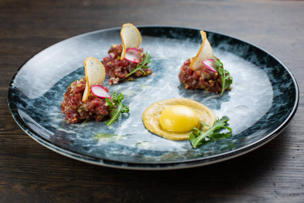 beef tartare with egg, white bread croutons and fresh radish. scrambled eggs with glaze. on a blue marble plate - tartar sauce imagens e fotografias de stock