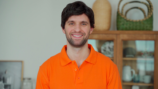 Portrait of a happy man in a orange shirt looking at the camera and smiling.