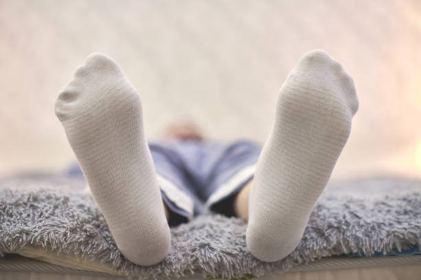 istock Woman resting on sofa in white striped socks, close up. 1299646328