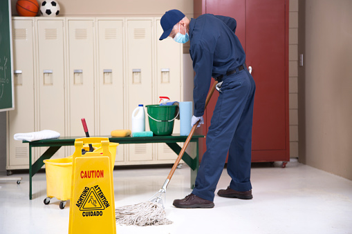 Senior adult Janitor keeps the floors cleaned and sanitized due to the virus