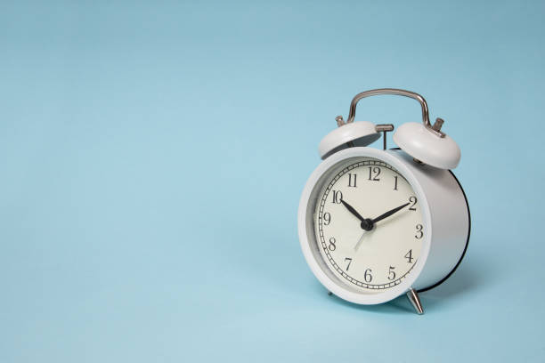 istock Retro alarm clock on blue background. Old fashioned alarm clock 1299648752