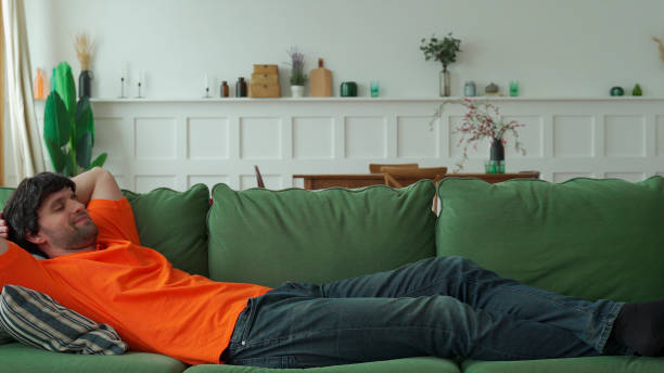 istock Happy man is resting on a comfortable sofa, resting with his eyes closed 1299648820