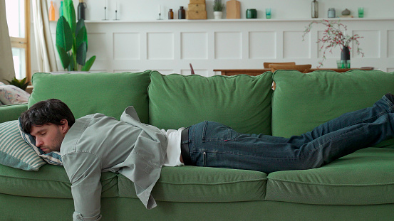 Joven exhausto llegó a casa después de que el trabajo se desplomó en el sofá photo