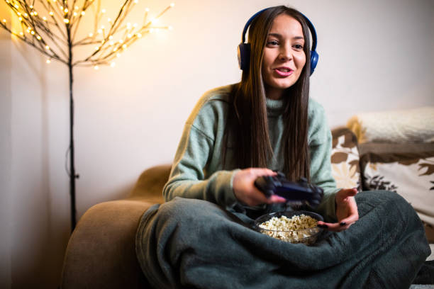 istock A pretty woman having fun playing video games and eating popcorn 1299649920
