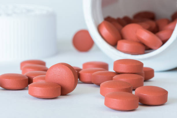 таблетки ибупрофена, вылитые из бутылки - ibuprofen стоковые фото и изображения