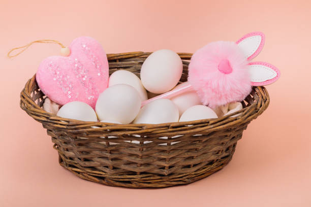 istock Easter. White eggs in a basket on a uniform pink background. Place for text. 1299651545