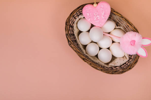 istock Easter. White eggs in a basket on a uniform pink background. Place for text. 1299651552
