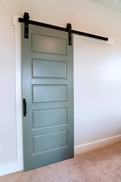 istock Closed sliding gray panel door with black handle against white wall of home 1299653855