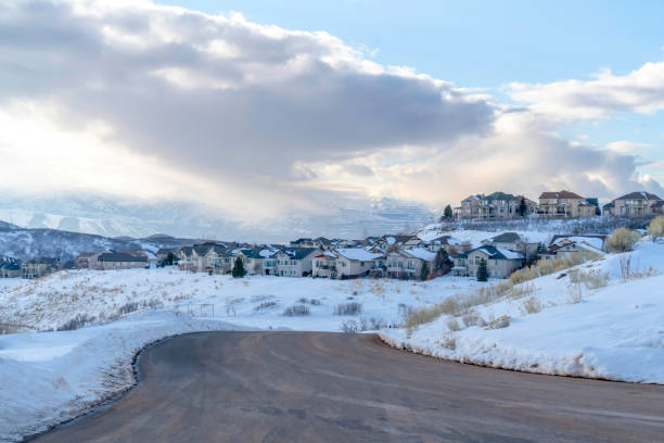 istock Curving road on snowy mountain setting with houses against cloudy blue sky 1299653865