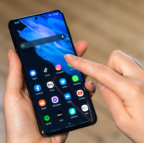 Glasgow, Scotland: Close-up on a woman holding a Samsung Galaxy S21 smart phone and selecting an app to run from the screen.