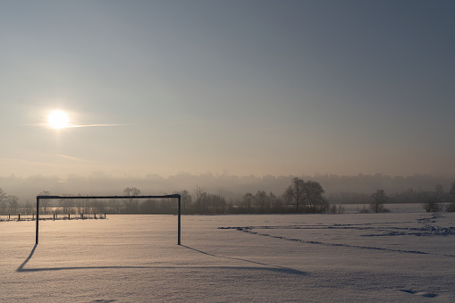Abandoned soccer field, seen in the morning, covered in snow