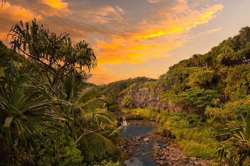 Tropical waterfall with green forests and a spectacular sunset in Hawaii