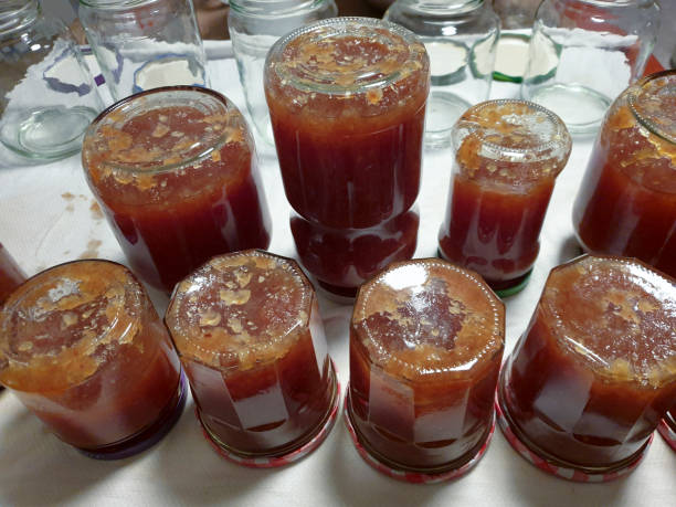 Tarros de vidrio en una fila llenos de mermelada de membrillo casera - foto de stock