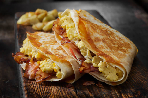 스크램블에그, 베이컨, 토마토, 치즈를 곁들인 접힌 아침 식사 토르티야 - 롤 샌드위치 뉴스 사진 이미지