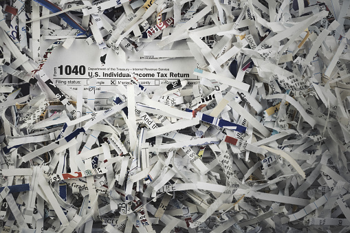 A 1040 US Individual Income Tax Return with shredded paper.