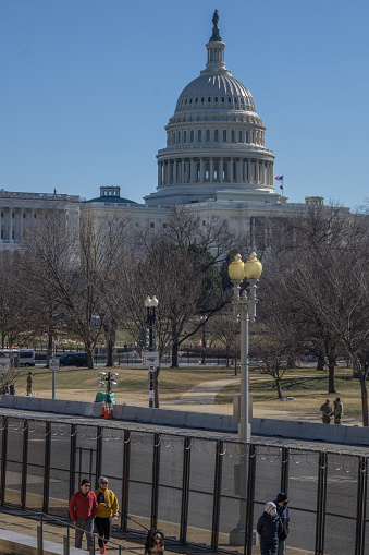 Washington D.C., January 30, 2021:  Fences were erected around Capitol after January 6 when pro-Trump protesters rallied in DC ahead of Electoral College vote count and some stormed into the Capitol. People walk outside the fence while National Guards soldiers on guard.