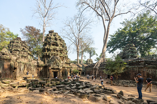 Siem Reap, Cambodia - January 22, 2020: Open doorway invites to explore an ancient temple with fallen stones and tangled roots in Ta Prohm Temple in Angkor, Cambodia. Ta Prohm is the temple in Siem Reap, Cambodia, built in the Bayon style largely in the late 12th and early 13th centuries by Khmer King Jayavarman VII.