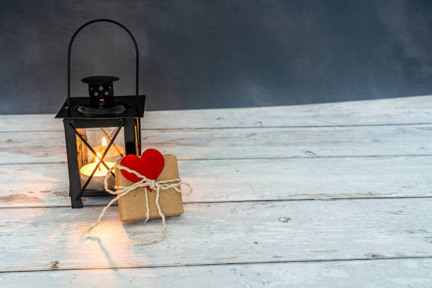 istock handmade gift with a red heart attached close to an illuminated lantern with dark background. eco friendly concept 1299663483