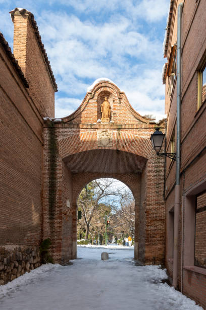 arch of saint bernard in the city of alcala de henares on a sunny day after a snowfall vertical view of arch of saint bernard in the city of alcala de henares with O'Donnel park in the background on a sunny day after a snowfall alcala de henares stock pictures, royalty-free photos & images